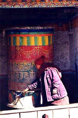 Monja Tibetana en los Himalayas, Nepal, activando la rueda de rezos o mantras.